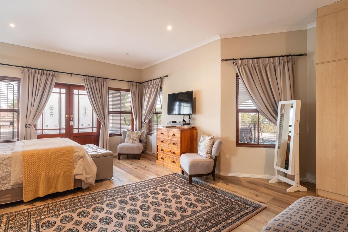Spacious bedroom featuring light wood-look flooring, built-in cabinetry, and double doors leading to an outdoor area, providing a bright and comfortable living space.