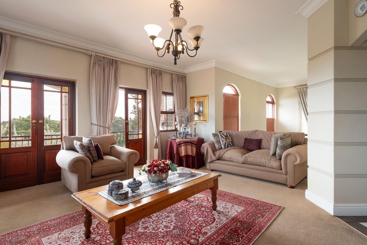 Spacious living room featuring classic crown molding, arched windows, and double timber-framed doors leading to an outdoor balcony area.