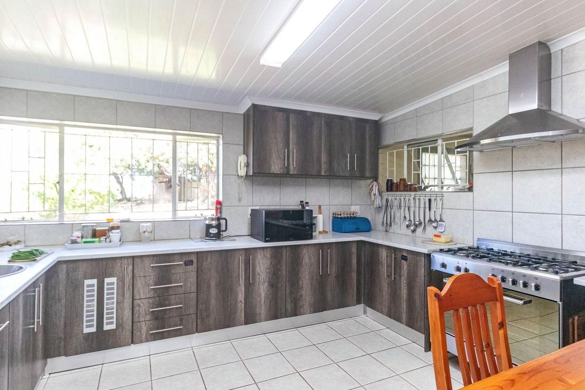 A functional kitchen featuring dark wood-grain cabinetry, tiled walls, a stainless steel extractor fan, and a gas stove.