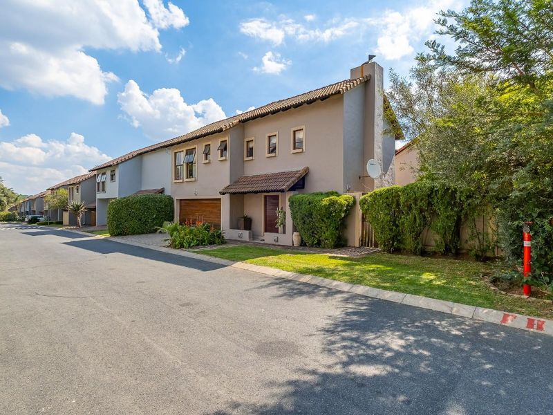 Street view of a multi-story residential townhouse complex featuring tiled roofs, plastered facades, and integrated garage doors.