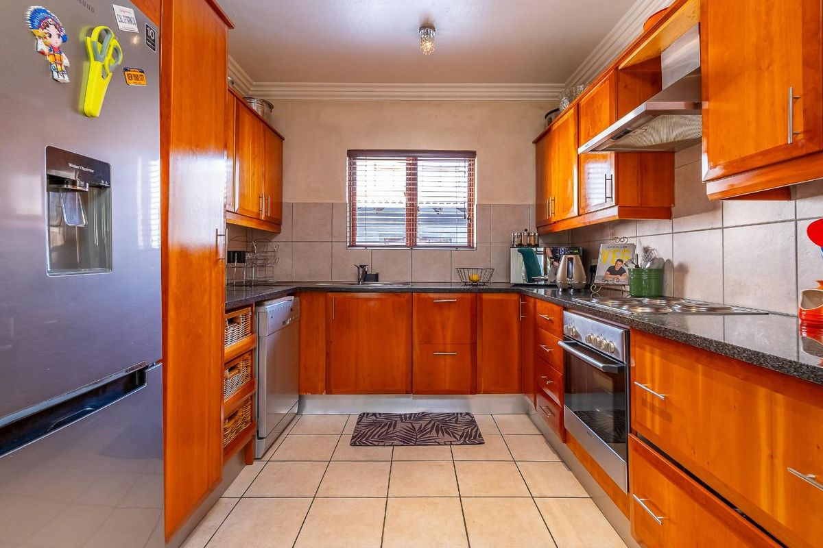 A functional kitchen featuring warm-toned wooden cabinetry, granite countertops, tiled backsplash, and built-in oven with extractor fan.
