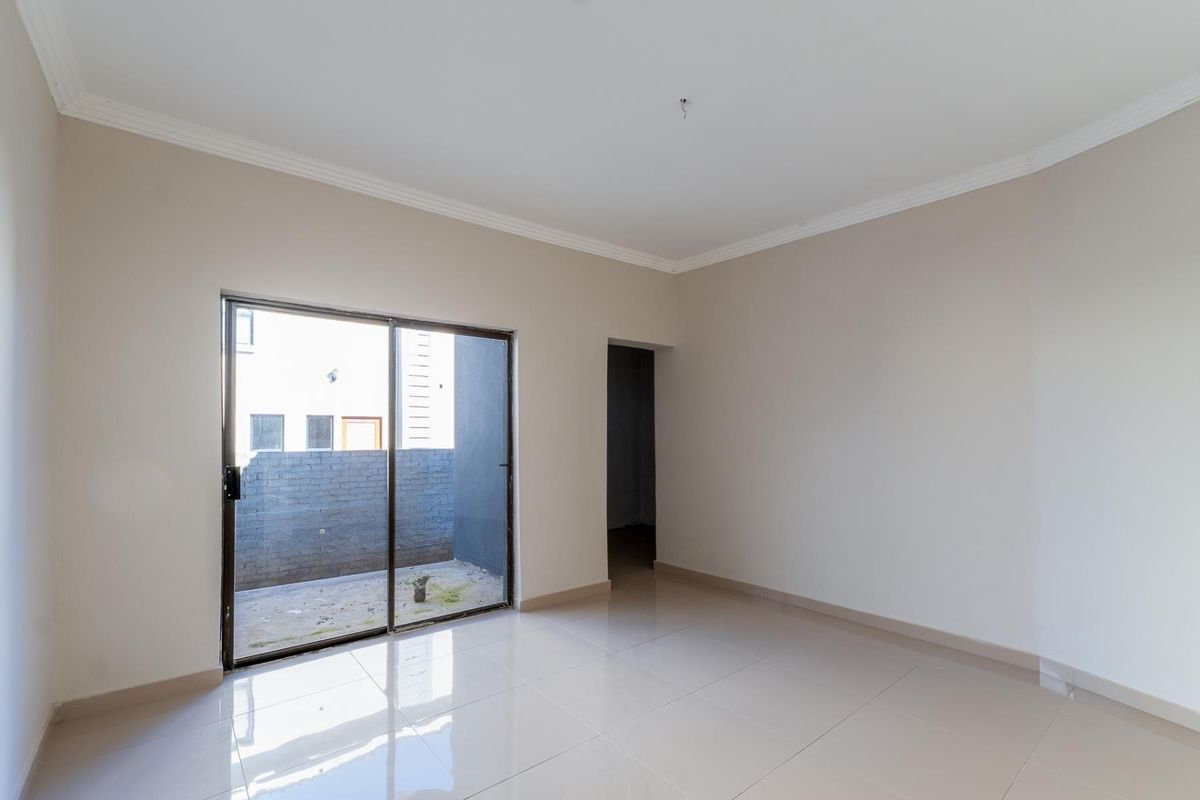 An empty, neutral-toned living room featuring large sliding glass doors that open to a private courtyard area.