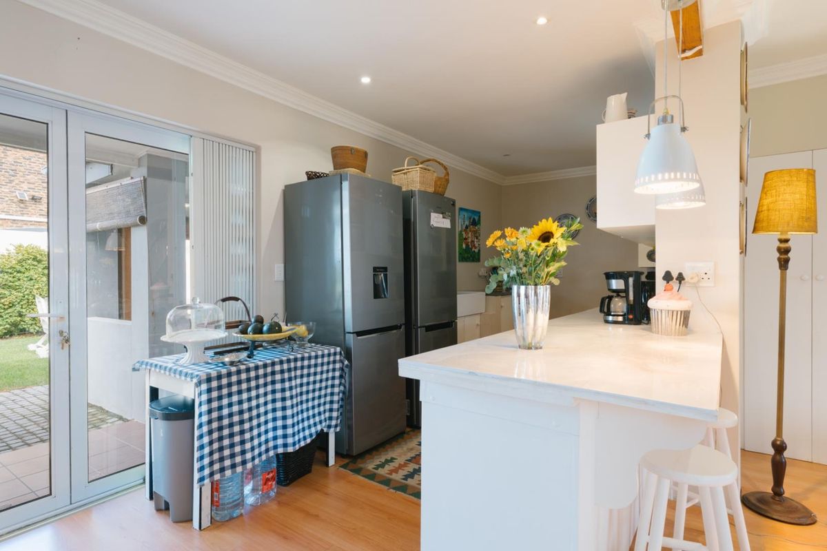 A bright kitchen featuring a central island with stone countertop, recessed lighting, and direct access to the outdoor patio through glass sliding doors.