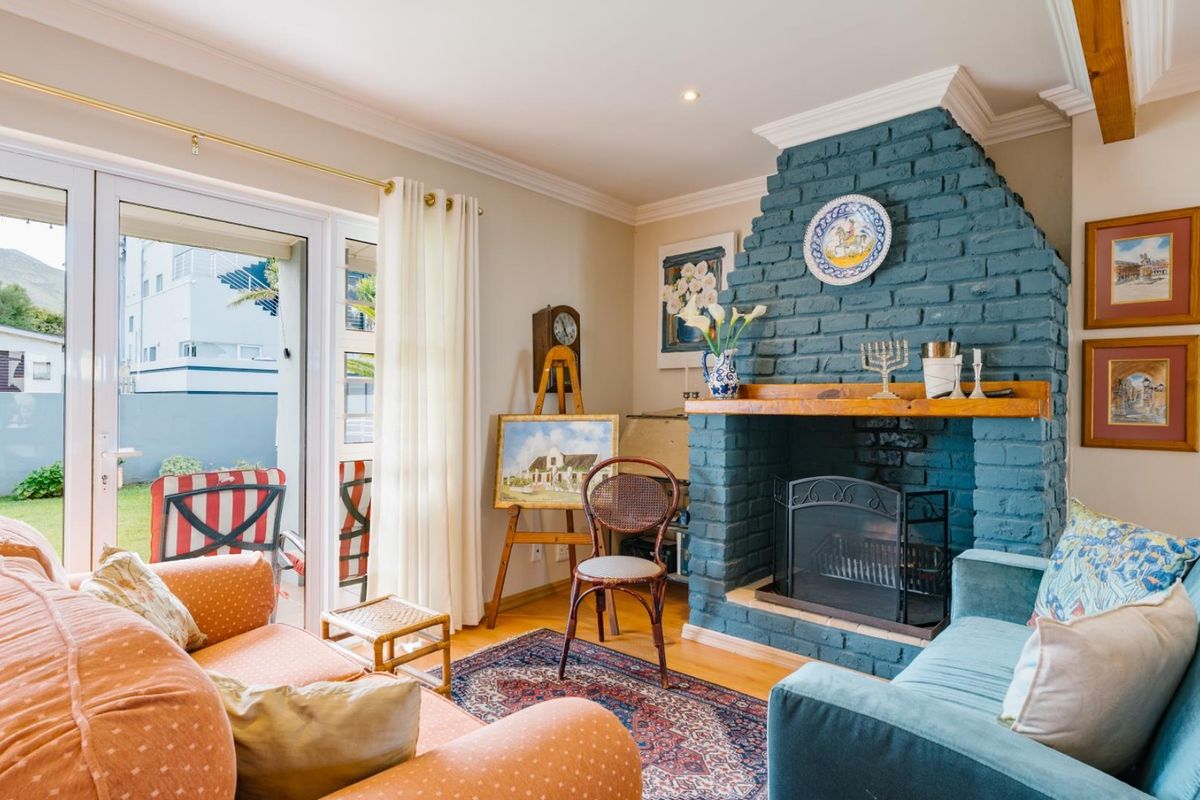 A cozy living room featuring a prominent blue painted brick fireplace with a wooden mantel and sliding glass doors leading to the patio.