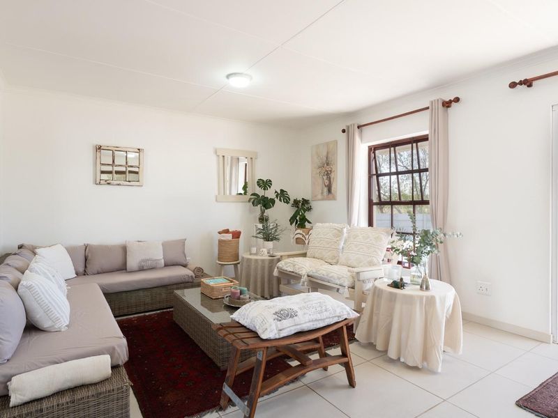 A bright living room featuring tiled flooring, large windows, and a glass door providing direct access to the outdoor patio area.