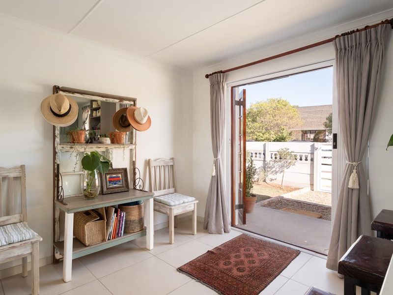 Bright living area featuring tiled flooring and direct access to a private outdoor patio through double doors.