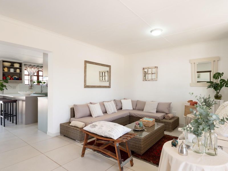 An open-plan living area featuring tiled flooring, a breakfast bar with integrated kitchen cabinetry, and direct access to an outdoor patio area.