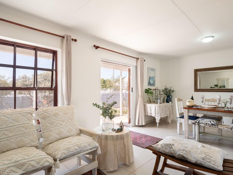 Bright open plan living and dining area featuring tiled flooring, large windows, and direct access to the outdoor patio area.