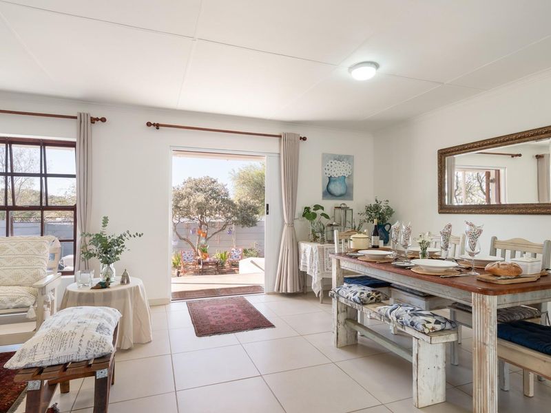 Bright open-plan living and dining area featuring tiled flooring, large windows, and sliding glass doors providing seamless access to the outdoor patio.