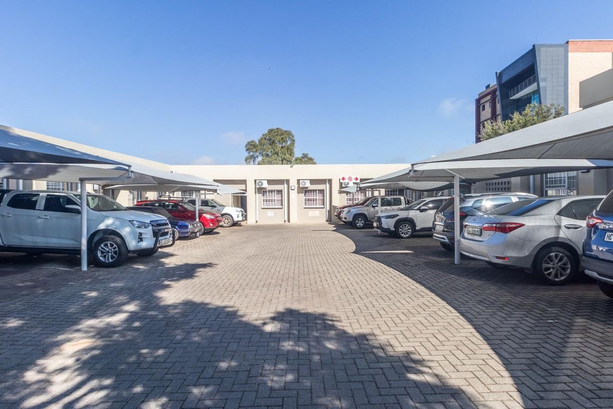 Commercial parking area featuring paved ground and multiple covered parking bays with shade cloth structures.