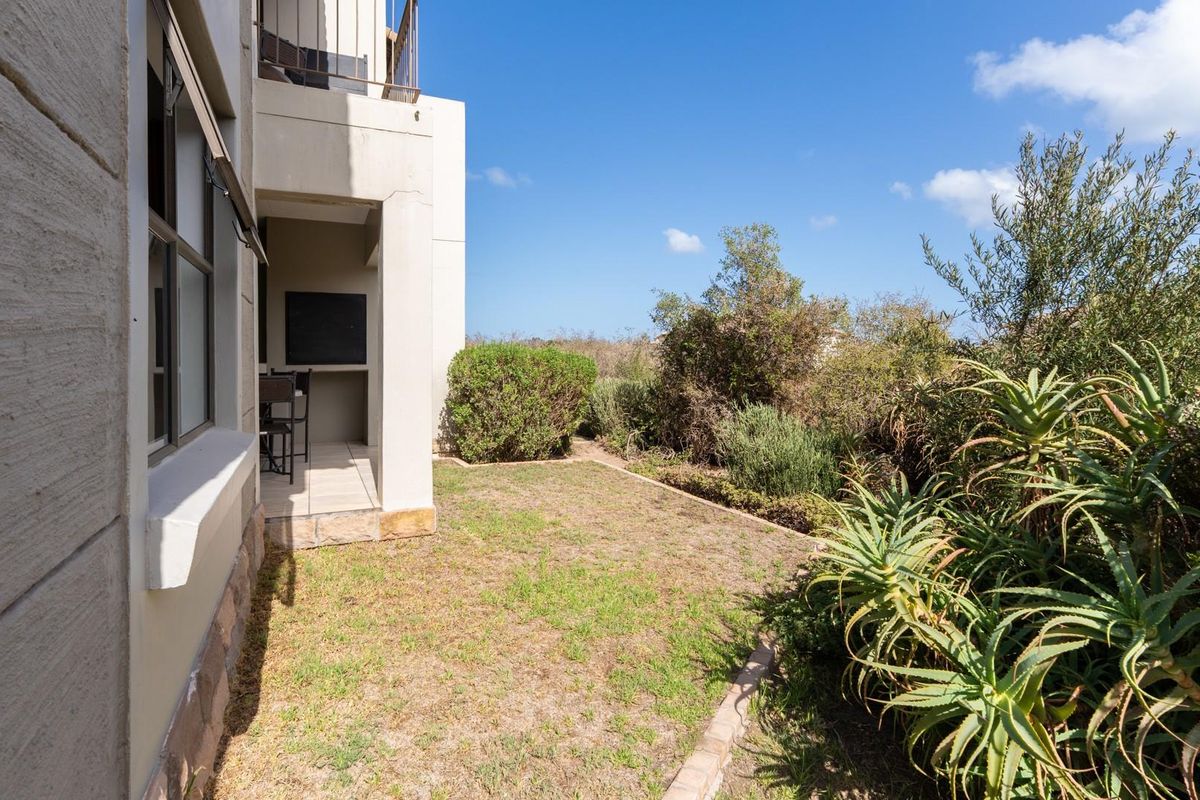 A private ground-floor patio area featuring a built-in braai, adjacent to a small private garden with established landscaping.