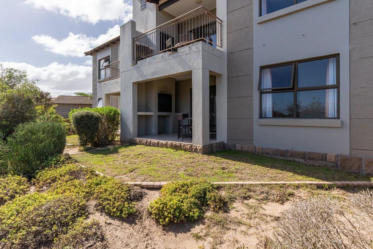 Ground floor apartment featuring a covered patio with a built-in braai, overlooking a private garden area with established landscaping.