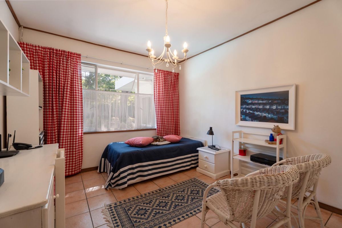 A bedroom featuring tiled flooring, a large window with natural light, and a classic chandelier fixture.