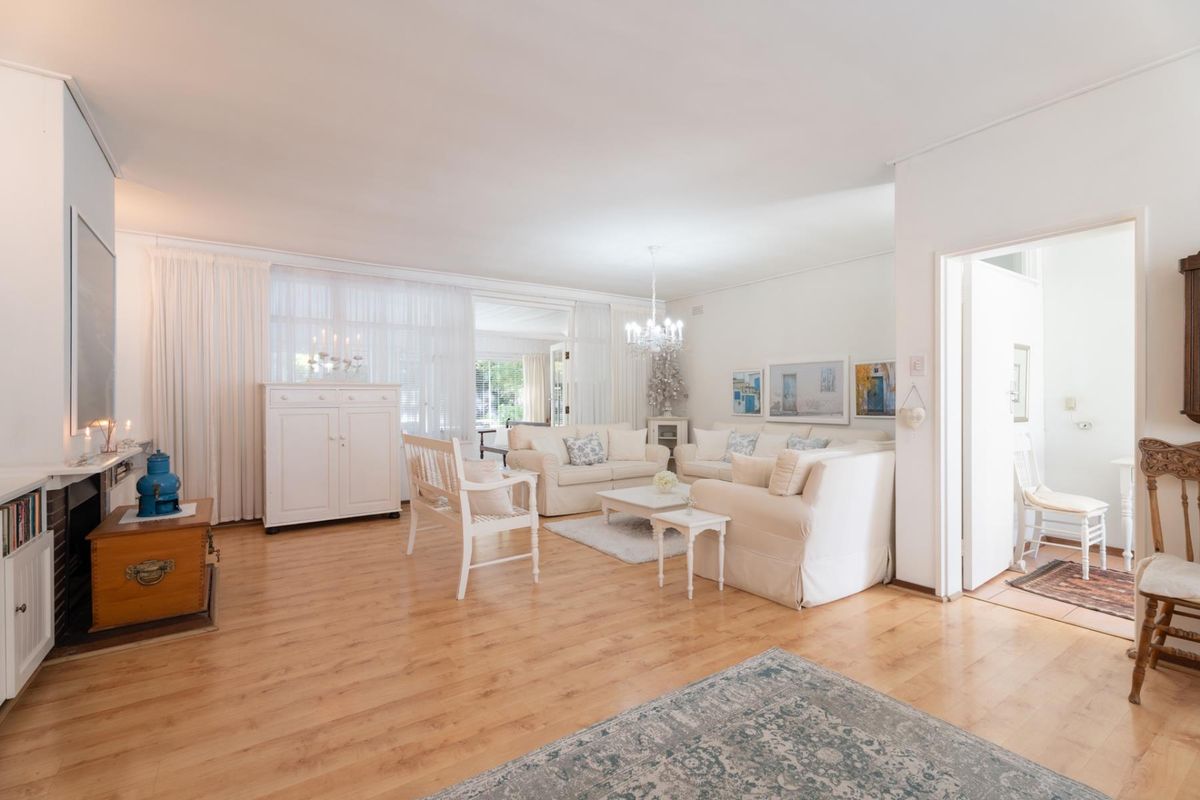 Spacious living room featuring light wood-look flooring, neutral walls, and large windows allowing for ample natural light.