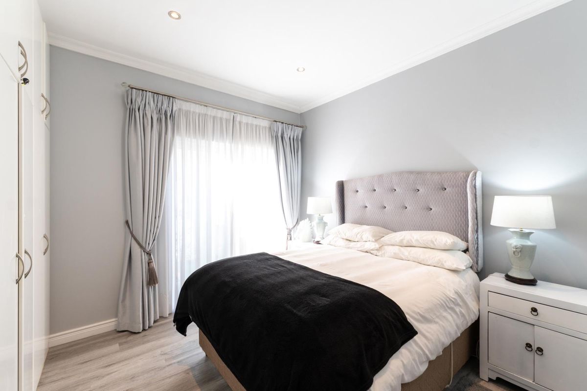 A well-maintained bedroom featuring built-in wardrobes, recessed ceiling lighting, and sliding glass doors providing access to the outdoors.