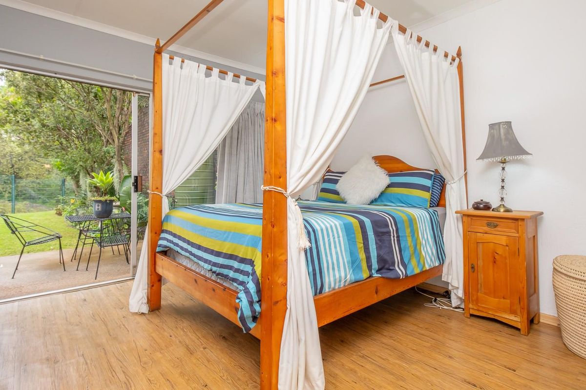 A bedroom featuring wood-look flooring and sliding glass doors that provide direct access to a private garden patio area.