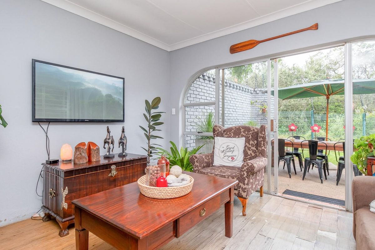 A bright living room featuring tiled flooring and large arched sliding glass doors that provide seamless access to an outdoor patio area.