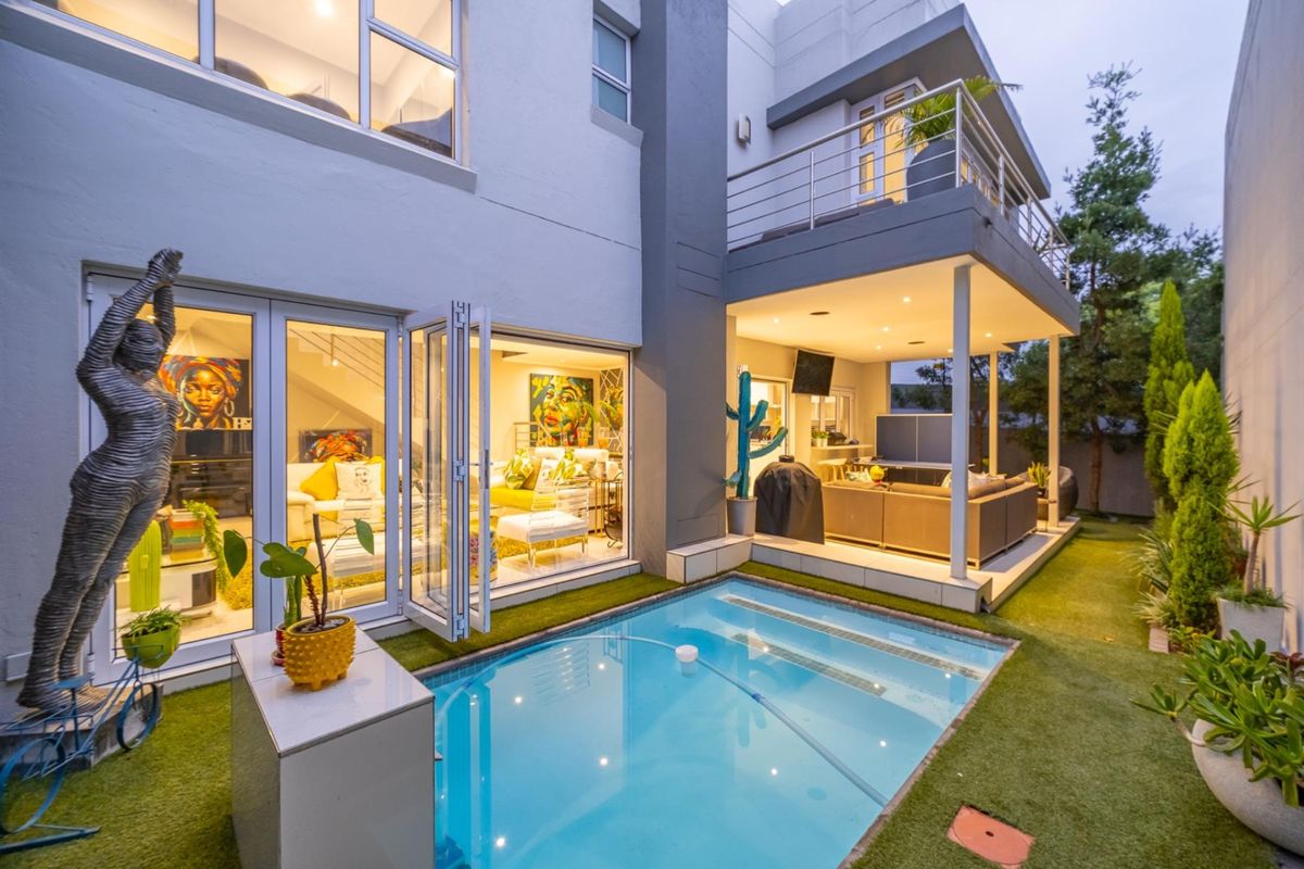 Modern townhouse exterior featuring a private swimming pool, covered patio area, and seamless indoor-outdoor flow through large folding glass doors.