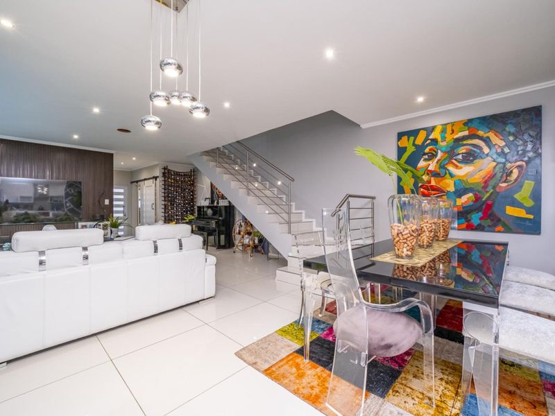 Spacious open-plan living and dining area featuring modern tiled flooring, recessed downlighting, and a contemporary staircase with stainless steel balustrades.