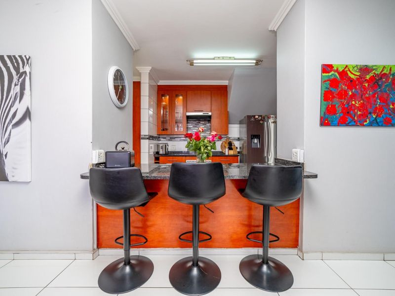 A functional kitchen featuring wooden cabinetry, granite countertops, and a breakfast bar area with tiled flooring.