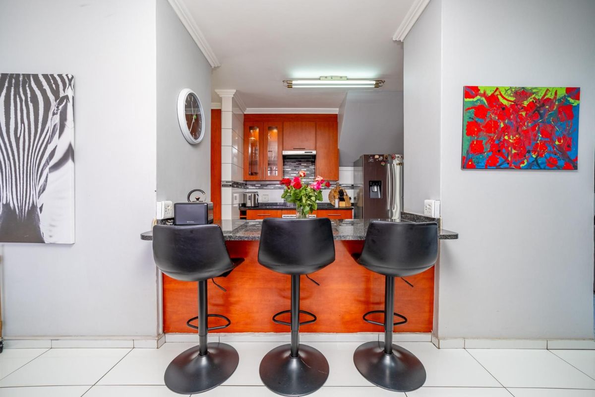 A functional kitchen featuring wooden cabinetry, granite countertops, and a breakfast bar area with tiled flooring.