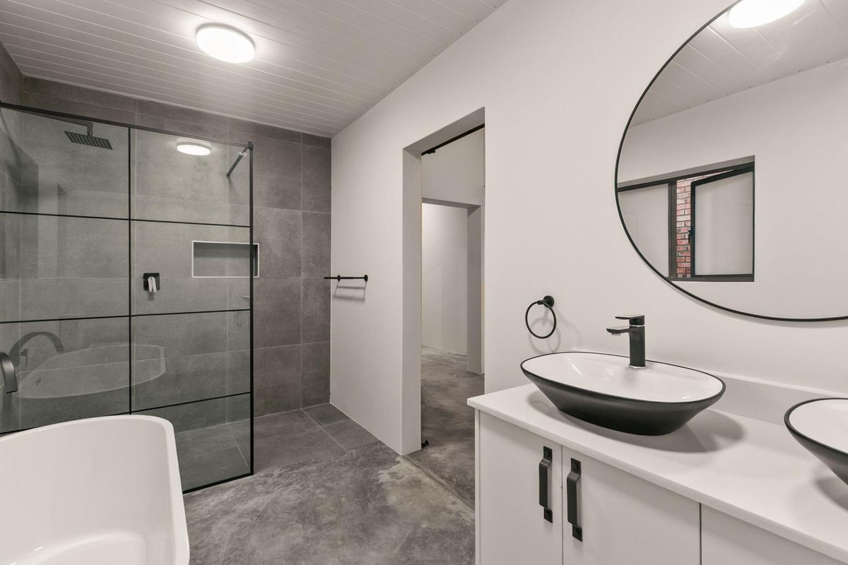 Modern bathroom featuring a walk-in shower with glass enclosure, dual vanity with vessel sinks, and contemporary matte black fixtures.
