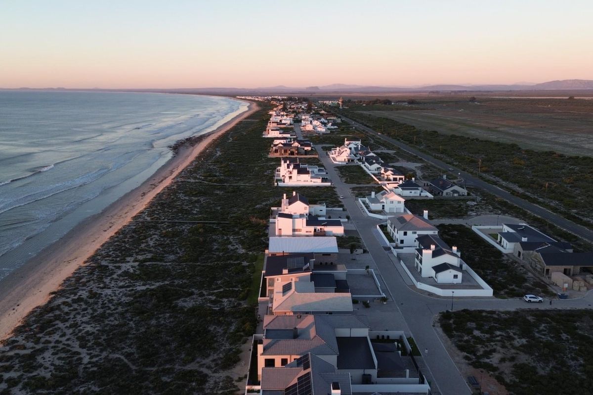 Aerial view of a coastal residential estate featuring modern homes situated along the shoreline at sunset.