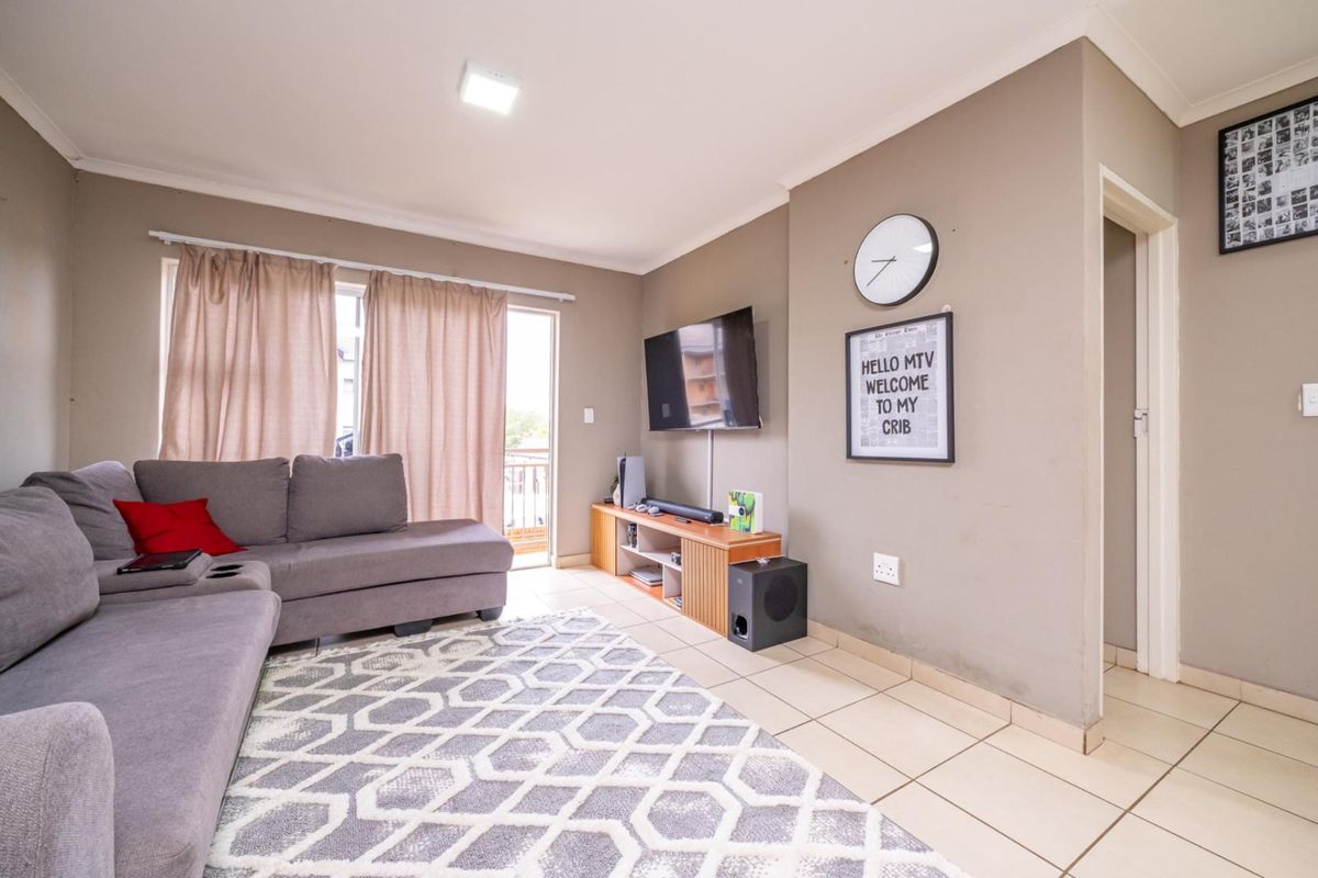 A functional living room featuring tiled flooring, neutral wall tones, and direct access to an outdoor balcony area.