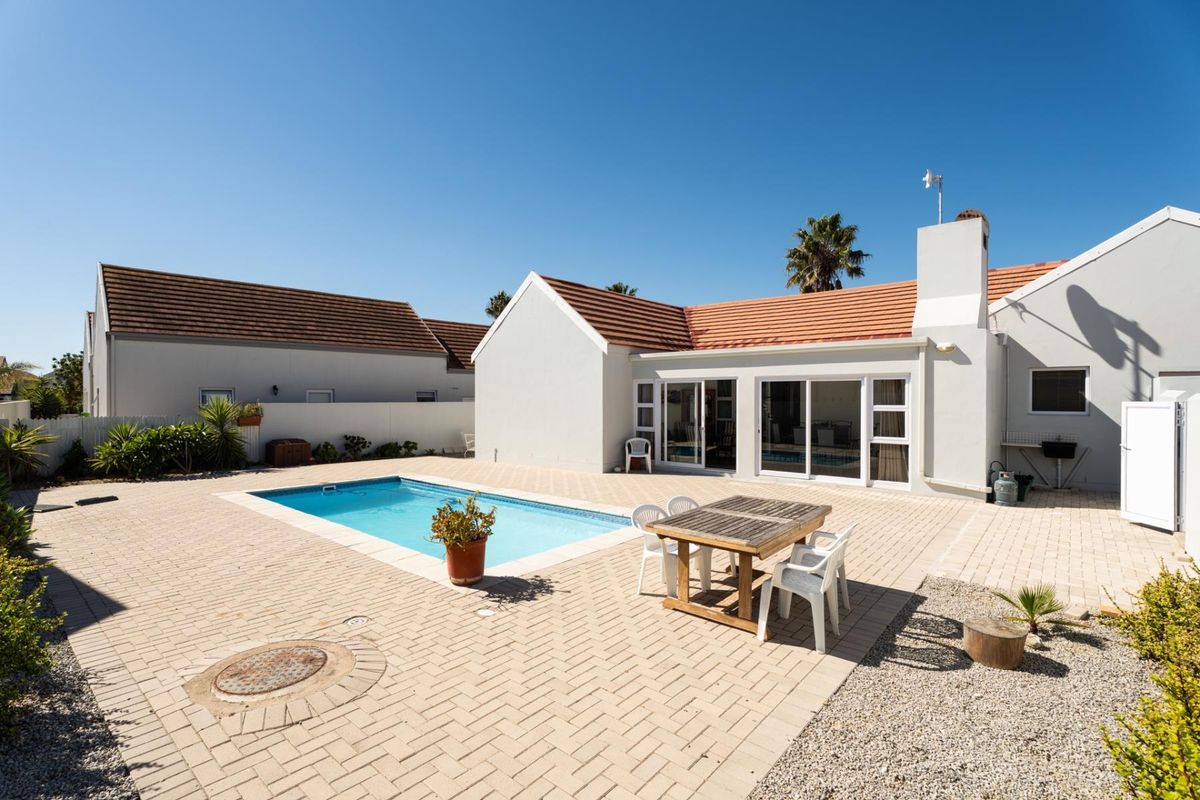 Rear exterior view featuring a paved patio area, a swimming pool, and sliding glass doors leading into the home.