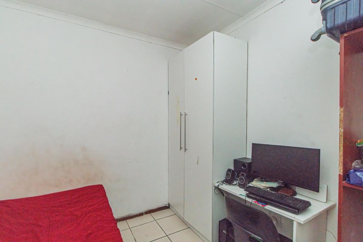 A compact bedroom featuring built-in white cabinetry and tiled flooring, requiring minor cosmetic updates to refresh the wall finishes.