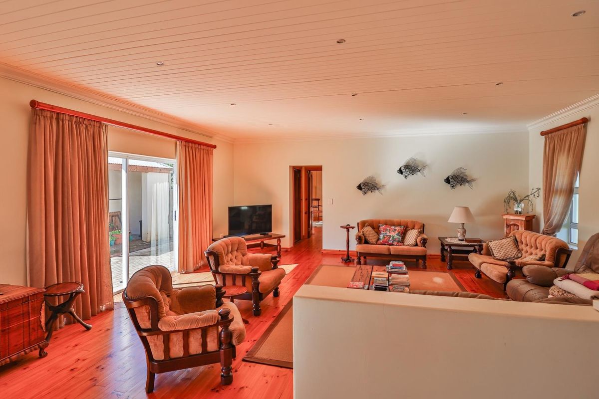 Spacious living room featuring warm timber flooring, recessed downlighting, and large sliding glass doors providing direct access to the outdoor patio area.