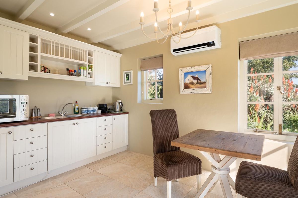 A bright kitchen featuring white cabinetry, a dark countertop, tiled flooring, and a wall-mounted air conditioning unit.