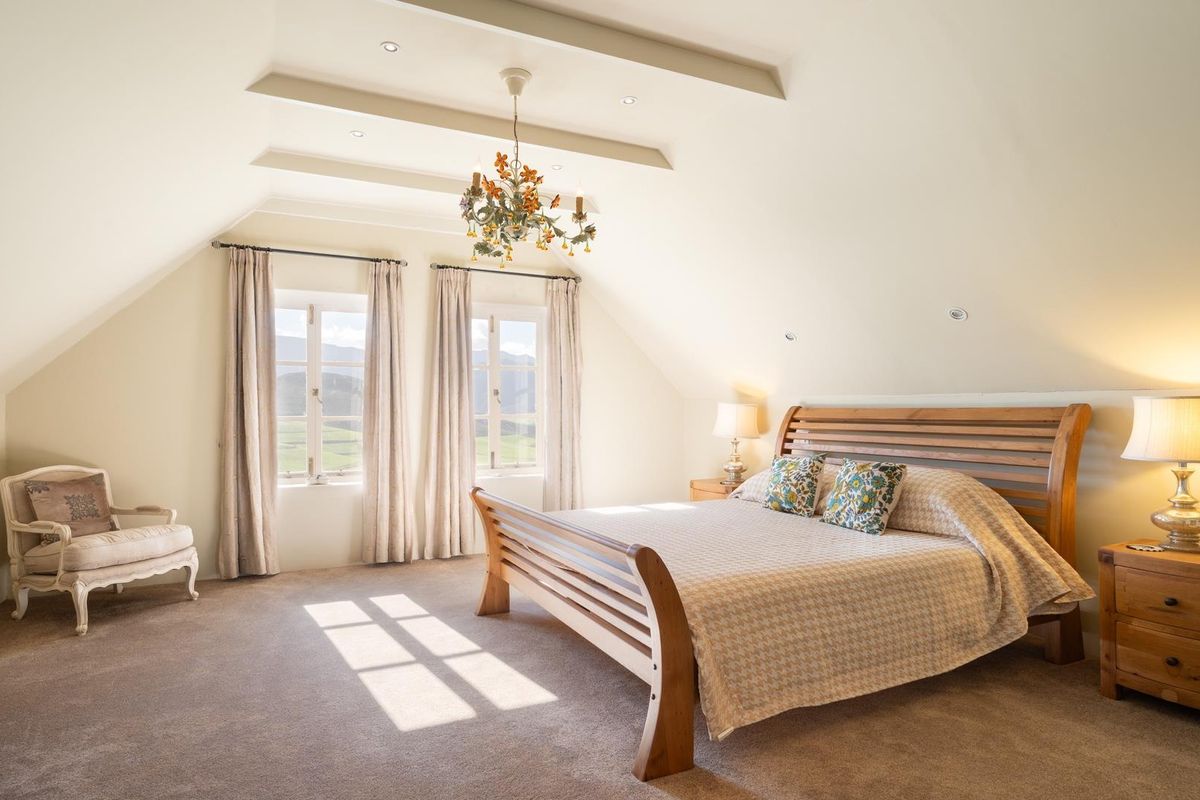Spacious attic bedroom featuring vaulted ceilings, recessed lighting, and large windows offering scenic landscape views.
