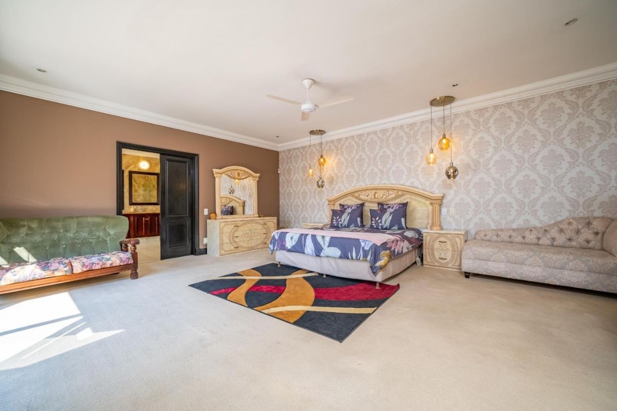 Spacious primary bedroom featuring patterned wallpaper, recessed lighting, a ceiling fan, and an en-suite bathroom access through double doors.