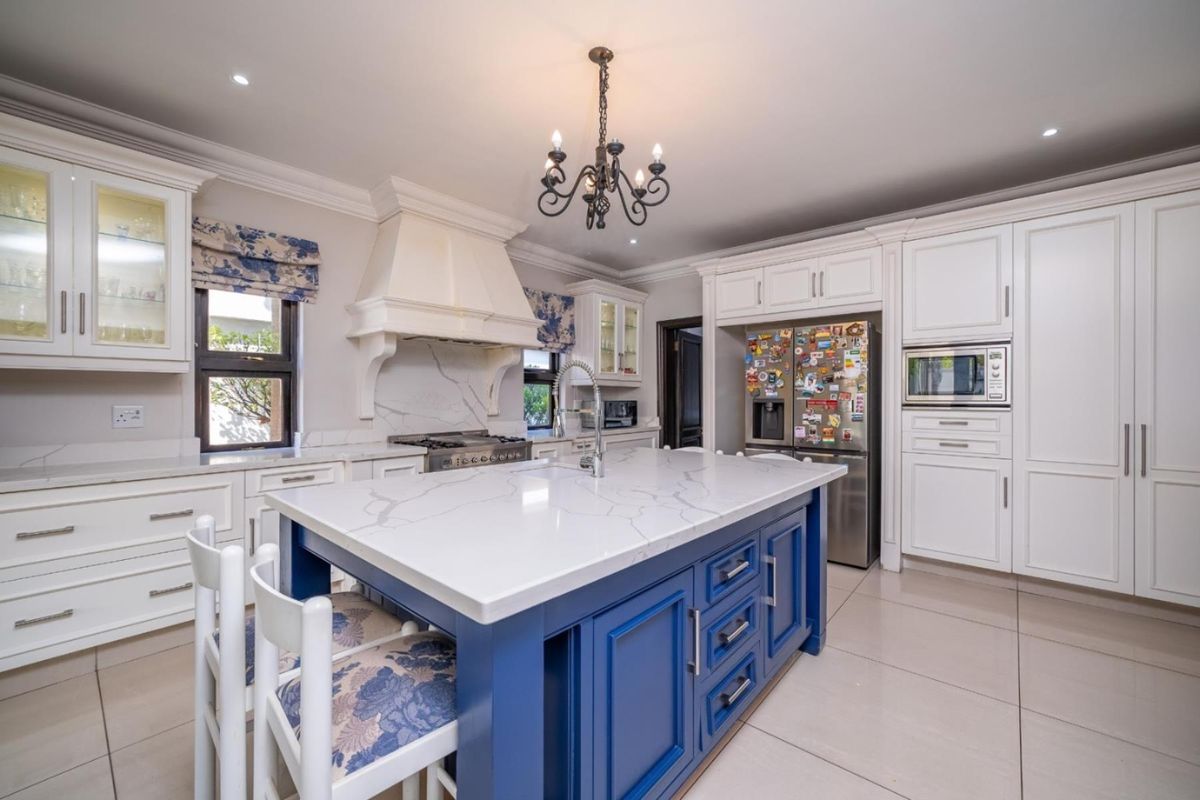 A well-appointed kitchen featuring a central island with stone countertops, custom cabinetry, a built-in oven, and a decorative range hood.