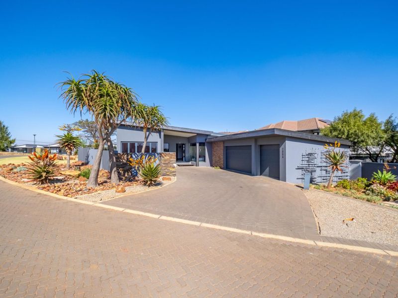 Modern single-story residence featuring a double garage, paved driveway, and attractive stone-clad architectural details set within a well-maintained landscaped garden.