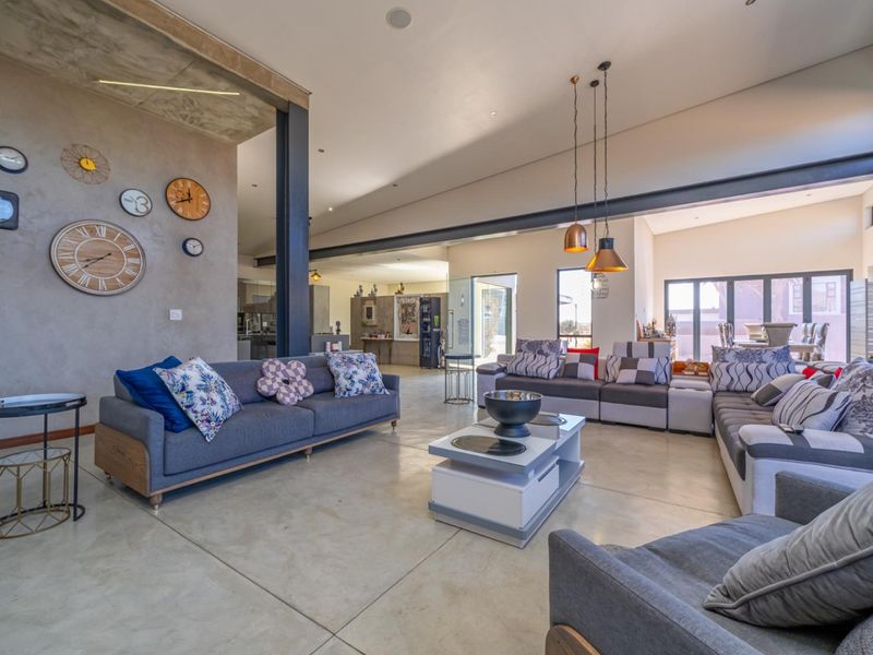 Spacious open-plan living area featuring polished concrete floors, exposed steel beams, and large sliding doors that provide seamless access to the outdoor space.