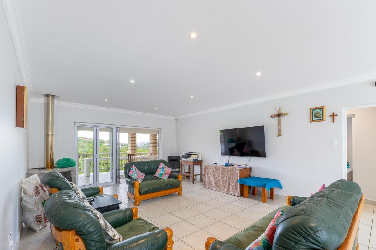 Spacious living room featuring tiled flooring, recessed ceiling lighting, and large sliding glass doors opening onto a covered patio with scenic views.
