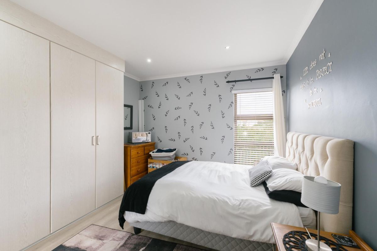 A well-maintained bedroom featuring built-in wardrobes, recessed ceiling lighting, and a window with fitted blinds.