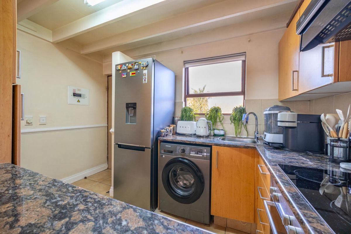 Functional kitchen featuring granite countertops, wooden cabinetry, integrated sink, and built-in hob with extractor fan.