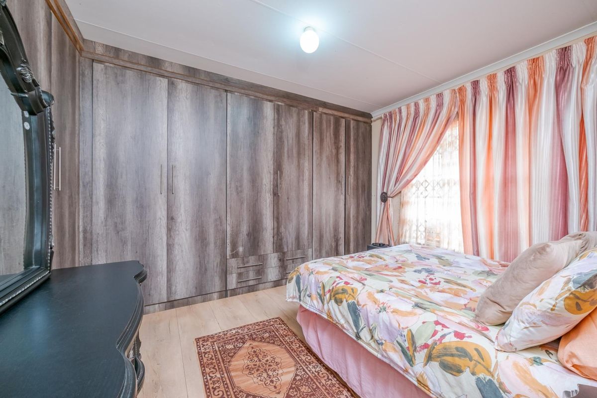 A bedroom featuring extensive built-in wooden cabinetry with integrated storage and light-toned laminate flooring.