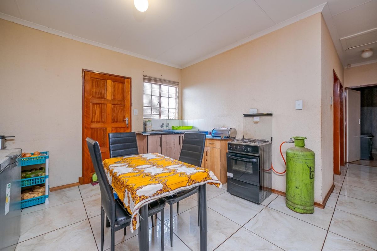 A functional kitchen and dining area featuring tiled flooring, wooden cabinetry, and a freestanding gas stove.