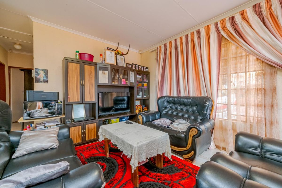 A living room featuring tiled flooring, large window with curtains, and built-in cabinetry.