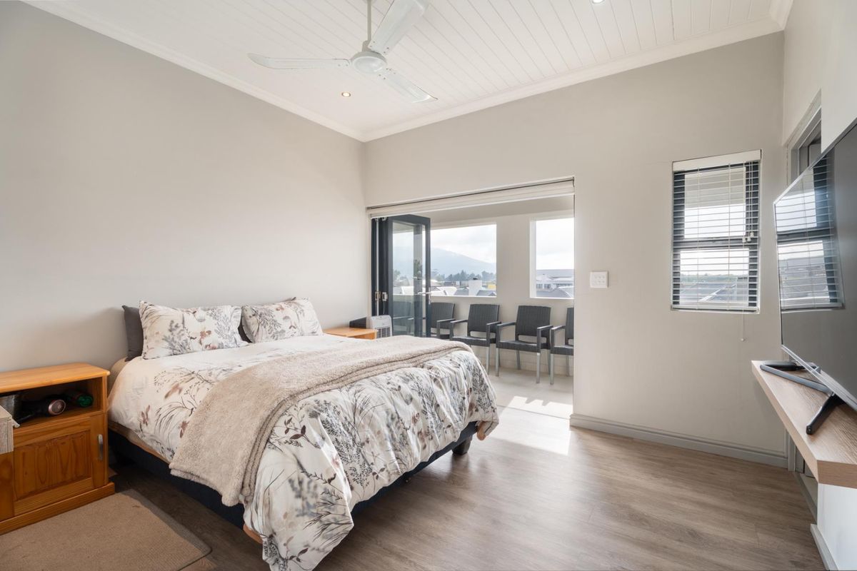 Spacious bedroom featuring laminate flooring, a ceiling fan, and bi-fold doors opening onto a private balcony with mountain views.