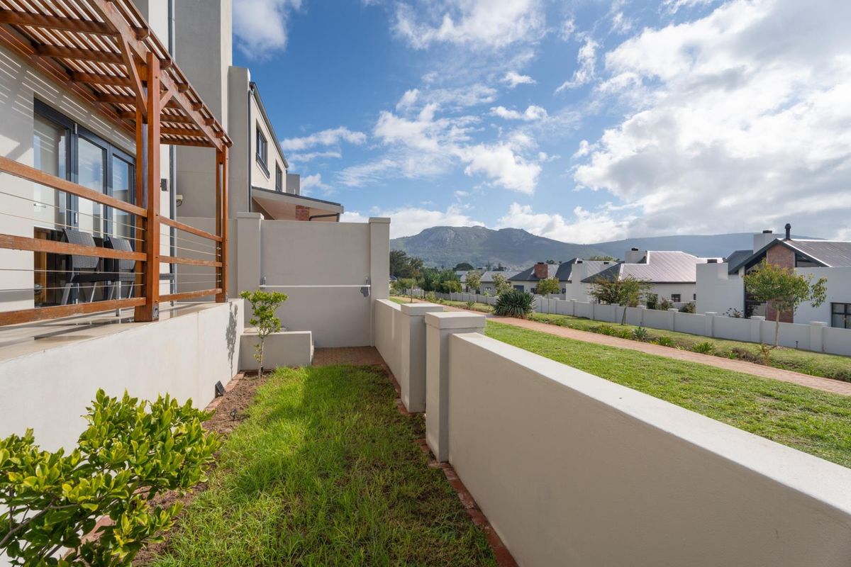 A well-maintained rear garden area featuring a timber pergola, low boundary walls, and scenic mountain views.