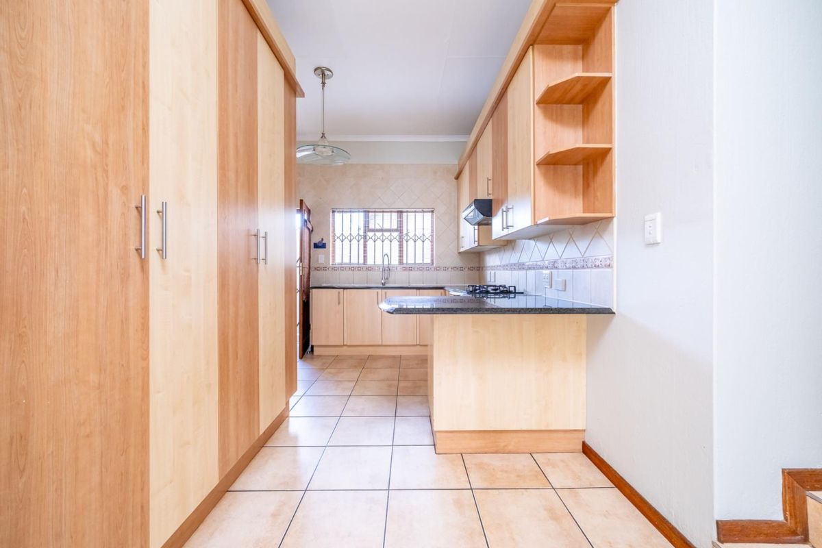 A functional kitchen featuring light wood cabinetry, granite countertops, a built-in gas hob, and tiled flooring.
