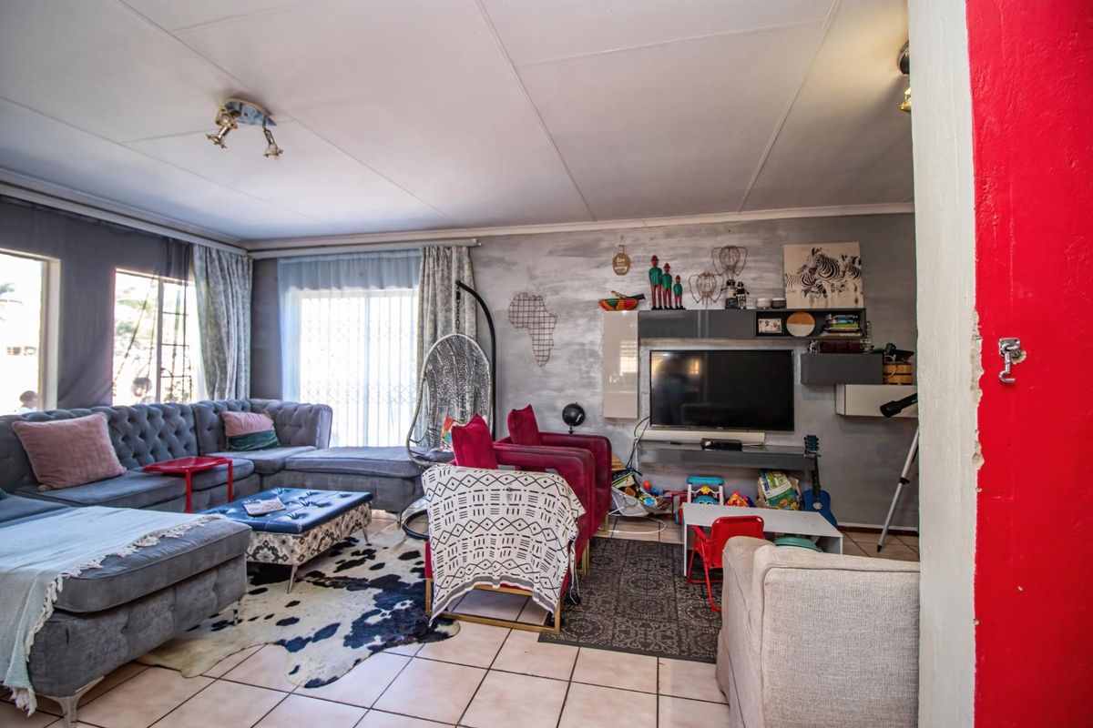Spacious living room featuring tiled flooring and a feature wall, providing a comfortable area for relaxation and family gatherings.