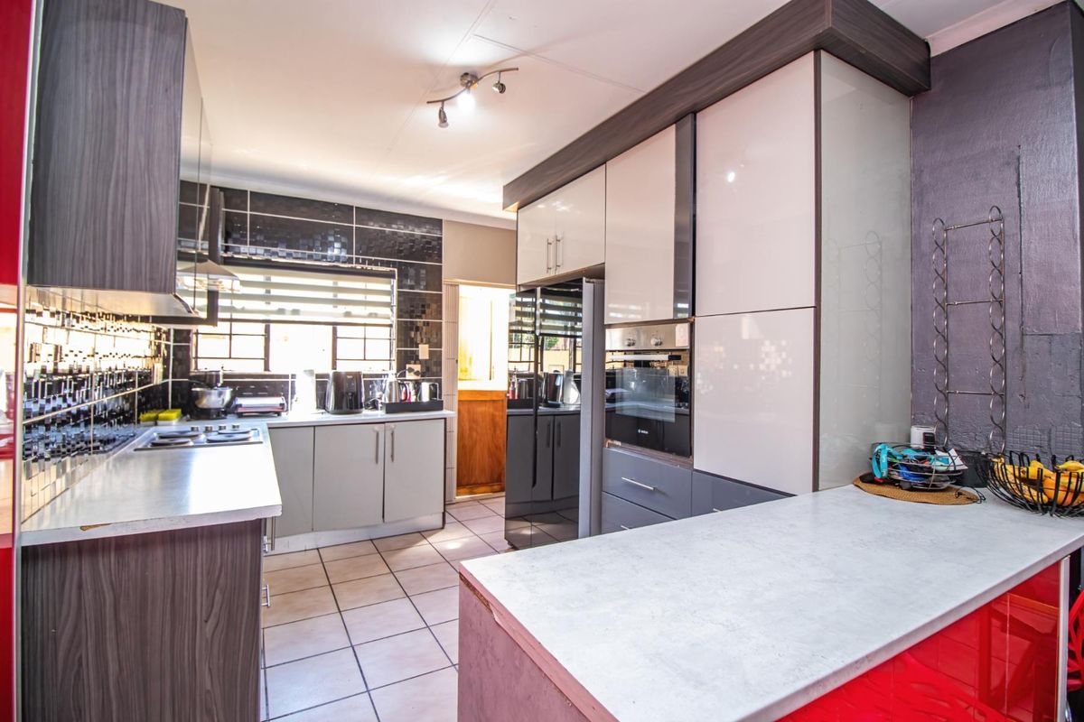 Modern kitchen featuring high-gloss cabinetry, built-in oven, integrated hob, and tiled flooring with ample counter space.