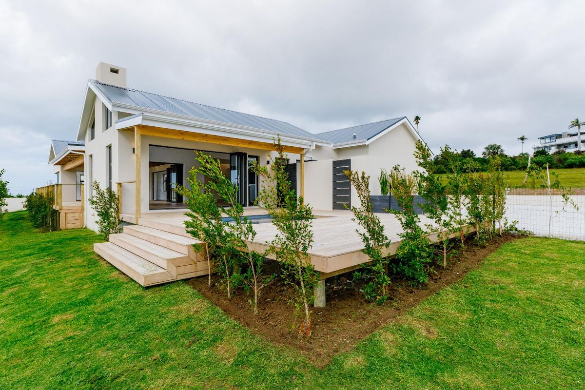 Modern rear exterior featuring a spacious timber deck, integrated plunge pool, bi-fold doors, and a well-maintained garden setting.