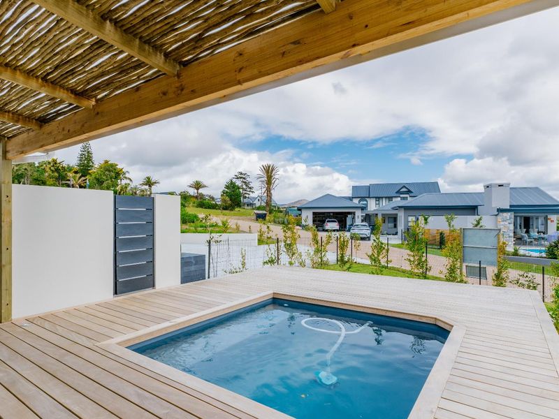 A well-maintained outdoor area featuring a timber deck, a plunge pool, and a wooden pergola, offering a pleasant view of the surrounding neighborhood.